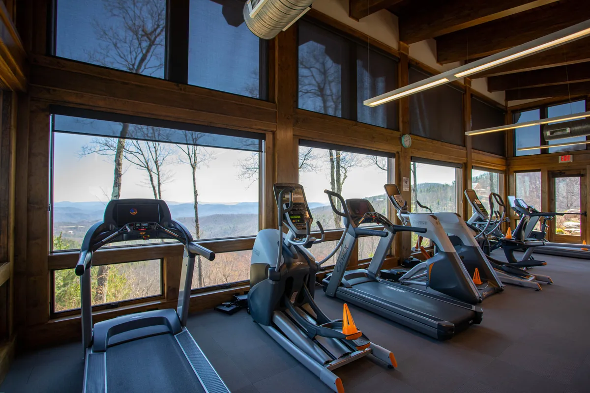 A well-lit fitness center with treadmills and ellipticals facing large windows, providing both natural light and scenic views. The open space appears easy to access and navigate, supporting active lifestyles for all guests.