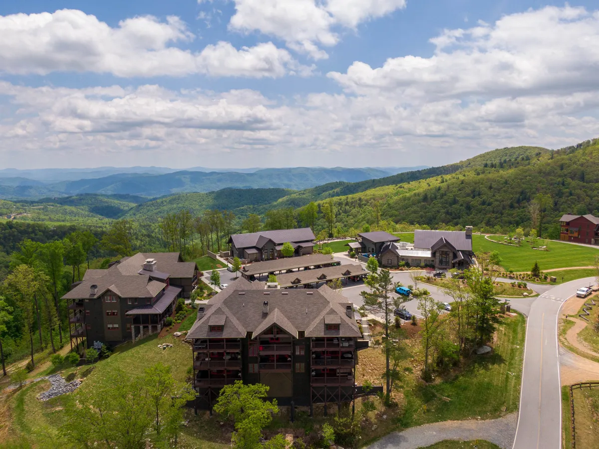 A sweeping view of a mountain range rising behind the resort’s modern buildings and landscaped gardens. The expansive setting invites visitors to imagine hiking or biking through the pristine wilderness with the resort nestled comfortably at its edge.