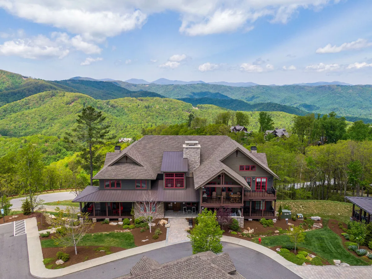 A view of the main building's exterior framed by surrounding mountains and beautifully landscaped gardens. The area is peaceful, with easy pathways and a welcoming atmosphere, hinting at nearby amenities—including covered parking just steps away.
