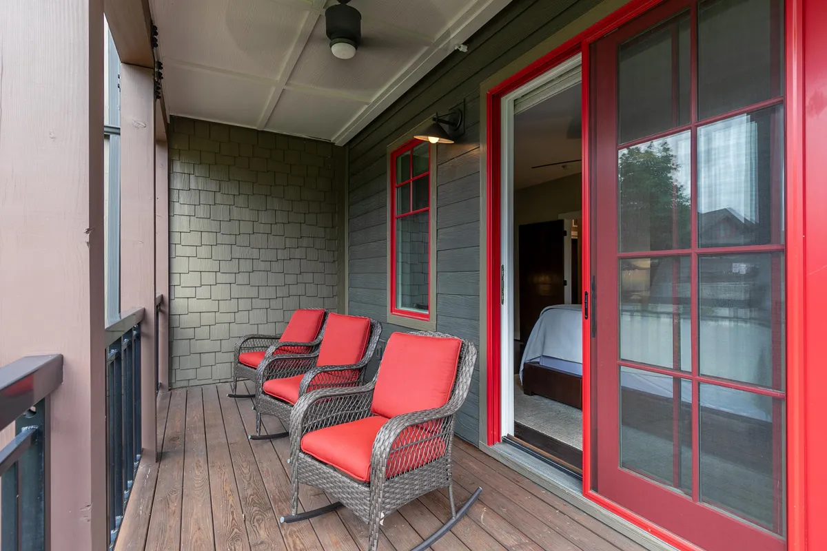 A private wooden deck with red chairs is positioned for relaxation and conversation, with a doorway leading inside. The setting is intimate and offers a direct connection to nature, ideal for taking in sunset views or morning coffee while surrounded by tranquility.